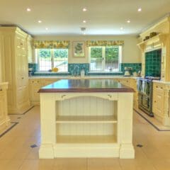 Spacious, bright kitchen with cream cabinets, a wooden-topped island, green tiled backsplash, stainless steel refrigerator, and large windows—perfect for Airbnb Management or Holiday Home Cleaning services.